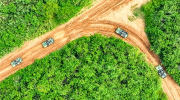 Armored vehicles rumble on muddy road